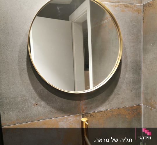 ברז זהב מותקן על קיר אריחים אפור